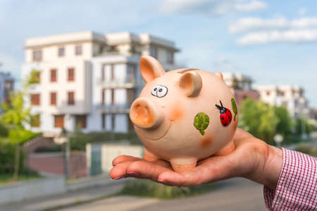 All savings money from pink ceramic piggy bank to pay for the dream home on blurred backgroundの写真素材