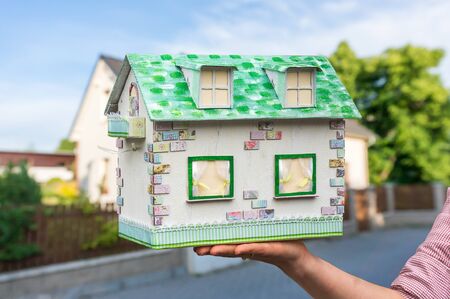 Real estate agent holding model house from paper on blurred backgroundの写真素材