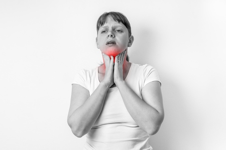 Woman with throat sore is holding her aching throat - black and white photoの写真素材