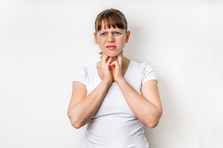 Woman with throat sore is holding her aching throat - isolated on white backgroundの写真素材