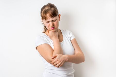 Woman with elbow pain is holding her aching armの写真素材