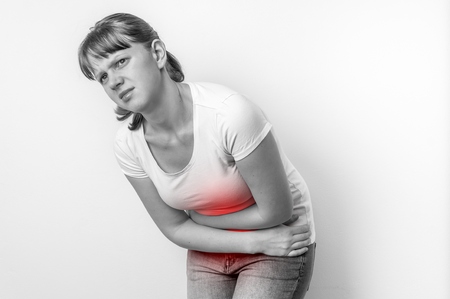 Woman with menstrual pain is holding her aching belly - black and white photoの写真素材