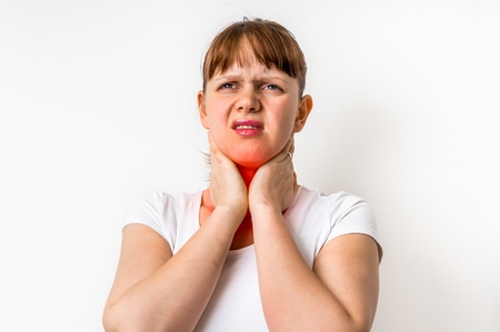 Woman with throat sore is holding her aching throat - body pain conceptの写真素材