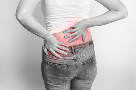 Woman with back pain holding aching parts - black and white photoの写真素材