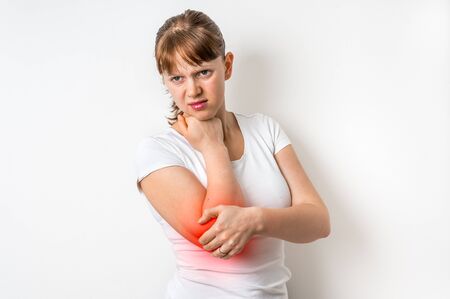Woman with elbow pain is holding her aching arm - body pain conceptの写真素材