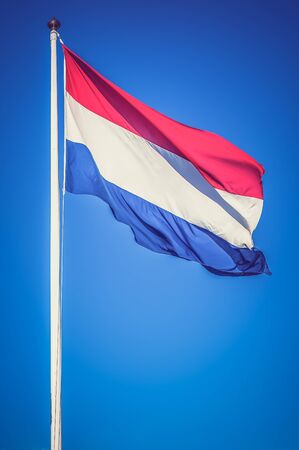 Netherlands flag on the blue sky background - retro and vintage styleの写真素材
