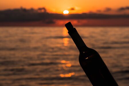 Beautiful sunset on sea and silhouette of a bottle of wineの写真素材