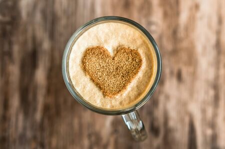 Cup of coffee with a heart shape symbol on wooden tableの写真素材