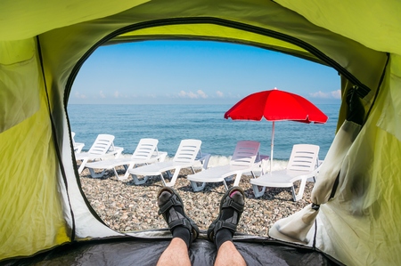 View from inside a tent on the sun loungers on a beach and red umbrellaの写真素材
