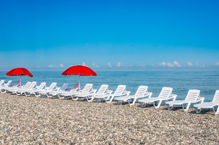 Sun loungers and red umbrellas on the beach in Batumi, Georgiaの写真素材