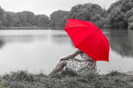 Beautiful girl with red umbrella near the pondの写真素材