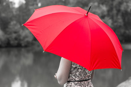 Beautiful girl with red umbrella near the pondの写真素材