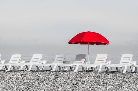 Red sun umbrella and plastic beach beds, black and white conceptの写真素材