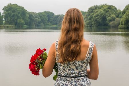 Girl by the lake holds a rosesの写真素材