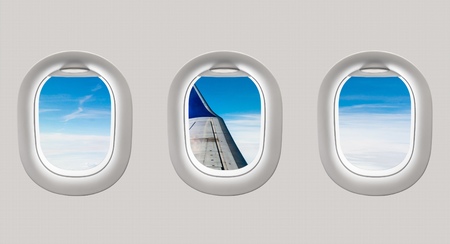 Looking out the windows of a plane to the aircraft wing, blue sky and cloudsの写真素材