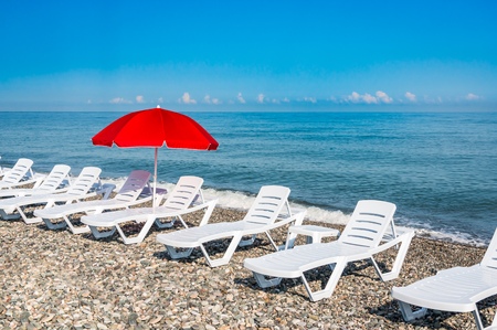 Sunbathing plastic beds and red umbrella on the beach near seaの写真素材