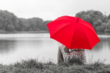 Beautiful girl with red umbrella near the pondの写真素材