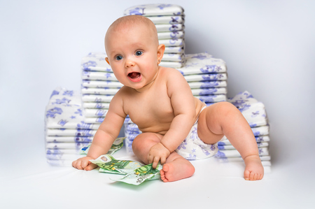 Cute baby with money isolated on blurry diapers background - expensive childcareの写真素材