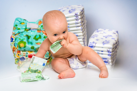 Cute baby with money isolated on blurry diapers background - expensive childcareの写真素材