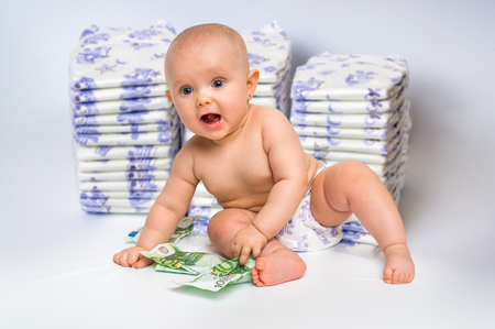 Cute baby with money isolated on blurry diapers background - expensive childcareの写真素材