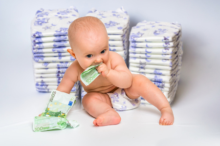 Cute baby with money isolated on blurry diapers background - expensive childcareの写真素材