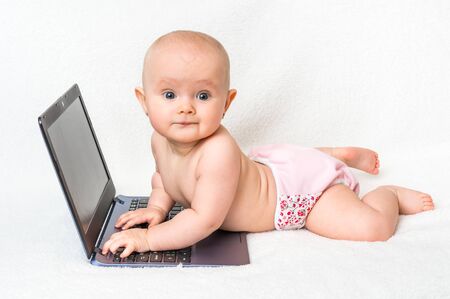 Cute baby typing on a laptop computer isolated on white blanketの写真素材