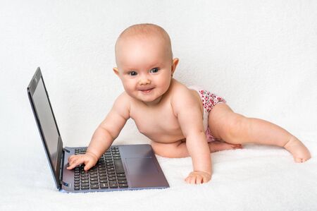 Cute baby with laptop computer on the white blanket backgroundの写真素材