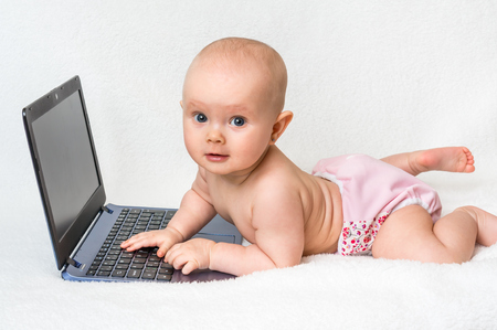 Cute baby typing on a laptop computer isolated on white blanketの写真素材