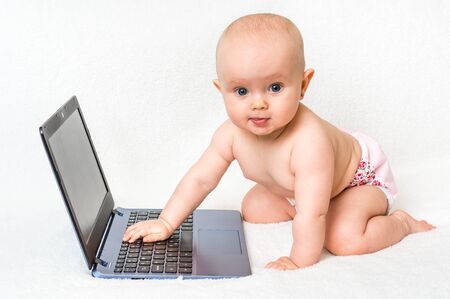 Cute baby typing on a laptop computer isolated on white blanketの写真素材