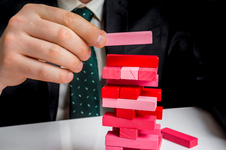 Successful businessman builds big tower with jenga bricks - planning, risk and strategy in businessの写真素材