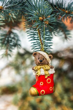 Teddy bear and red sock, Christmas toy on a Christmas tree under snowの写真素材