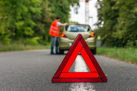 Broken car on the road and red warning triangleの写真素材