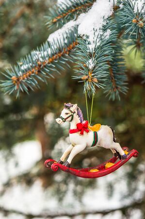 Rocking horse and snowy pine tree decorated for Christmas toy on branchの写真素材