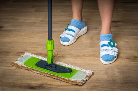 Woman with mop mopping wooden laminate floor at homeの写真素材