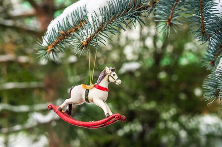 Rocking horse and snowy pine tree decorated for Christmas toy on branchの写真素材