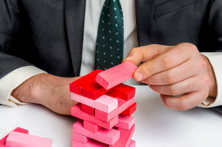 Successful businessman builds big tower with jenga bricks - planning, risk and strategy in businessの写真素材