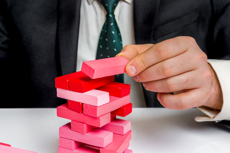 Successful businessman builds big tower with jenga bricks - planning, risk and strategy in businessの写真素材