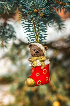 Teddy bear and red sock, Christmas toy on a Christmas tree under snowの写真素材