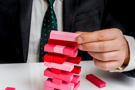 Successful businessman builds big tower with jenga bricks - planning, risk and strategy in businessの写真素材