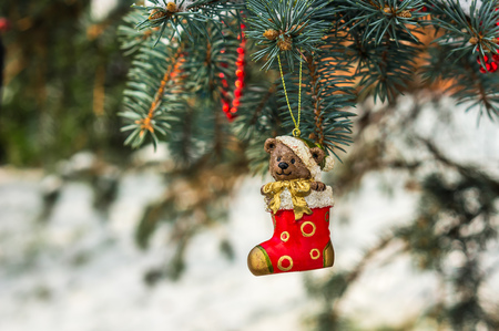 Teddy bear and red sock, Christmas toy on a Christmas tree under snowの写真素材