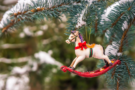 Rocking horse and snowy pine tree decorated for Christmas toy on branchの写真素材