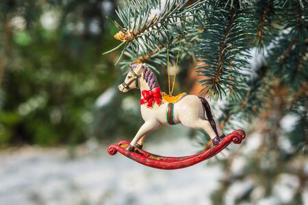 Rocking horse, closeup of Christmas tree decoration on snowy pine branchの写真素材