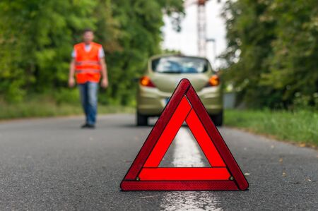 Broken car on the road and red warning triangleの写真素材