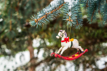 Rocking horse, closeup of Christmas tree decoration on snowy pine branchの写真素材