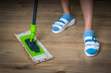Woman with mop mopping wooden laminate floor at homeの写真素材