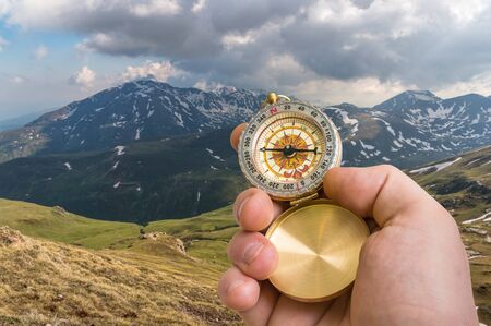 Traveler man with compass seeking a right way in the mountains - navigation conceptの写真素材