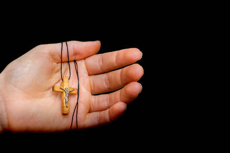 Wooden cross in female hand isolated on black background - religion conceptの写真素材