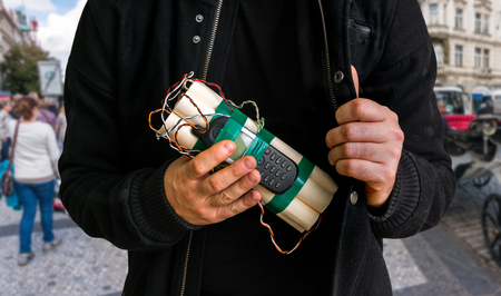 Dangerous terrorist on street with a lot of people and dynamite bomb in hand - terrorism conceptの写真素材