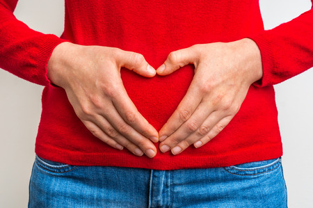 Female hands showing sign of heart on red jumperの写真素材