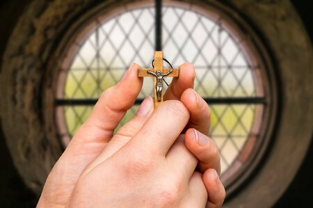 Female hands with wooden cross and window inside the church - religion conceptの写真素材